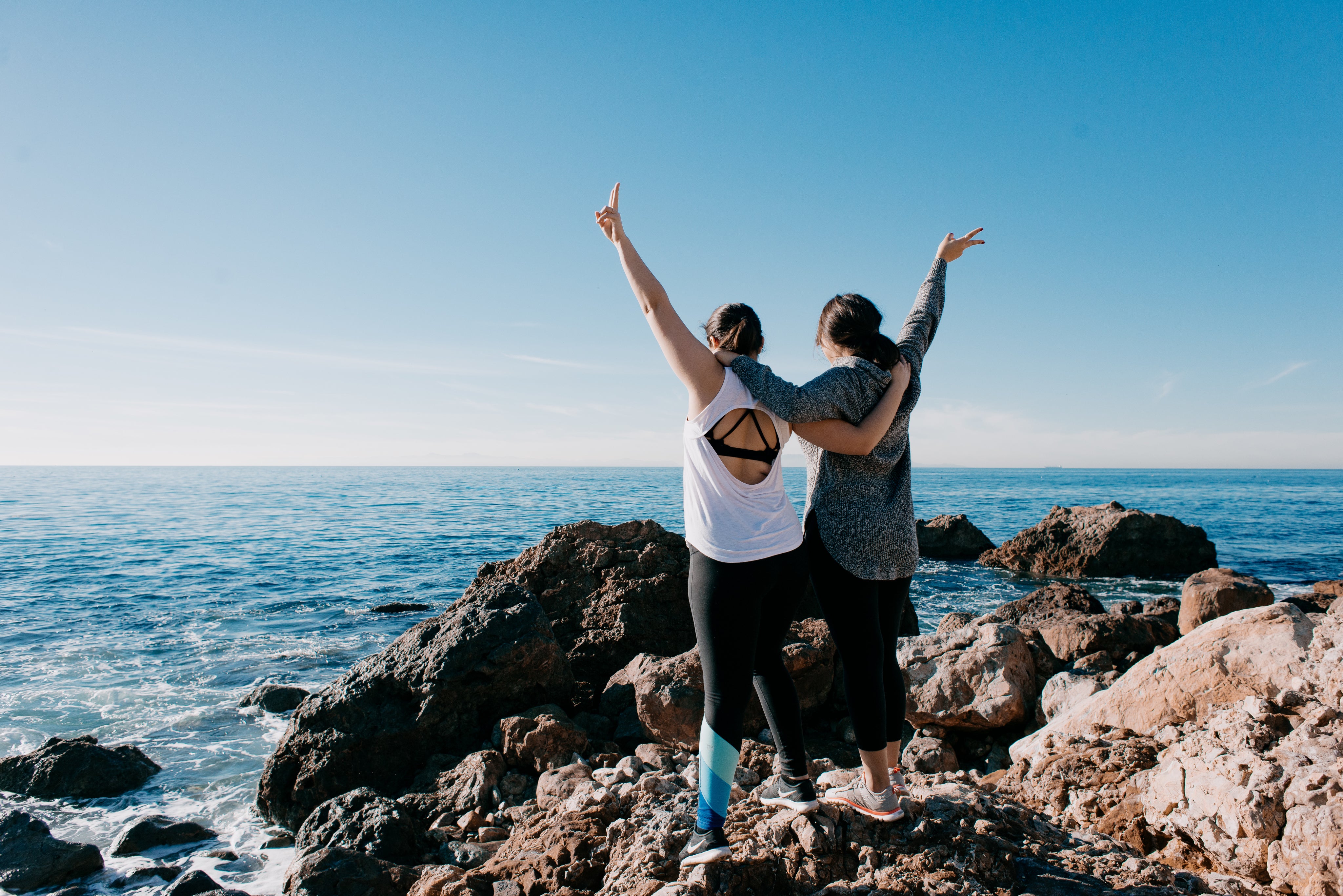 files/women-arm-in-arm-raise-their-hands-in-peace-sign-on-beach.jpg